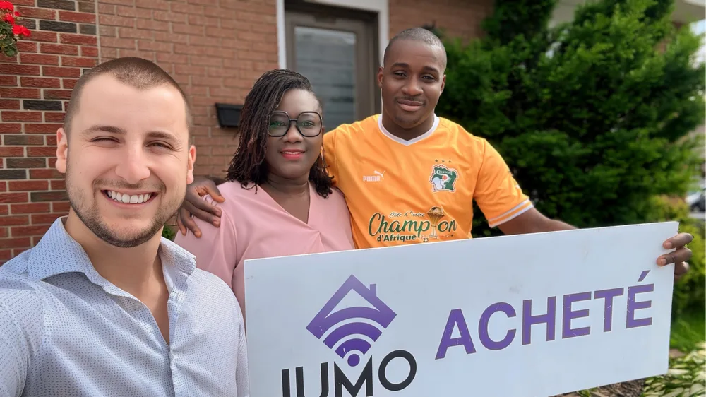 Couple client de Jumo Immobilier avec la pancarte « Acheté » après leur achat