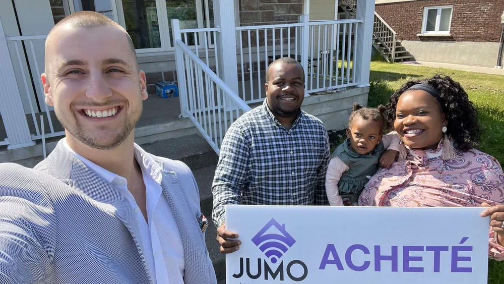 Famille cliente de Jumo Immobilier avec la pancarte « Acheté » devant leur nouvelle maison